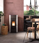 Tänd pelletskamin med svart front och vita sidor placerad mot en varmrosa vägg