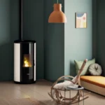 Tänd pelletskamin placerad mot en ljusgrön vägg