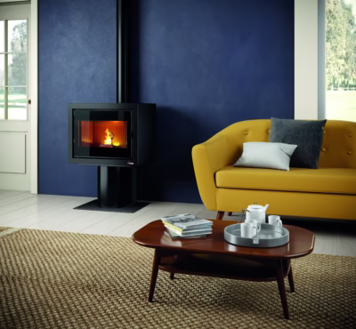 Tänd svart kamin placerad mot en mörkblå vägg i ett vardagsrum